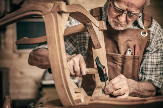 Craftsperson constructing a solid wood chair in a furniture workshop.